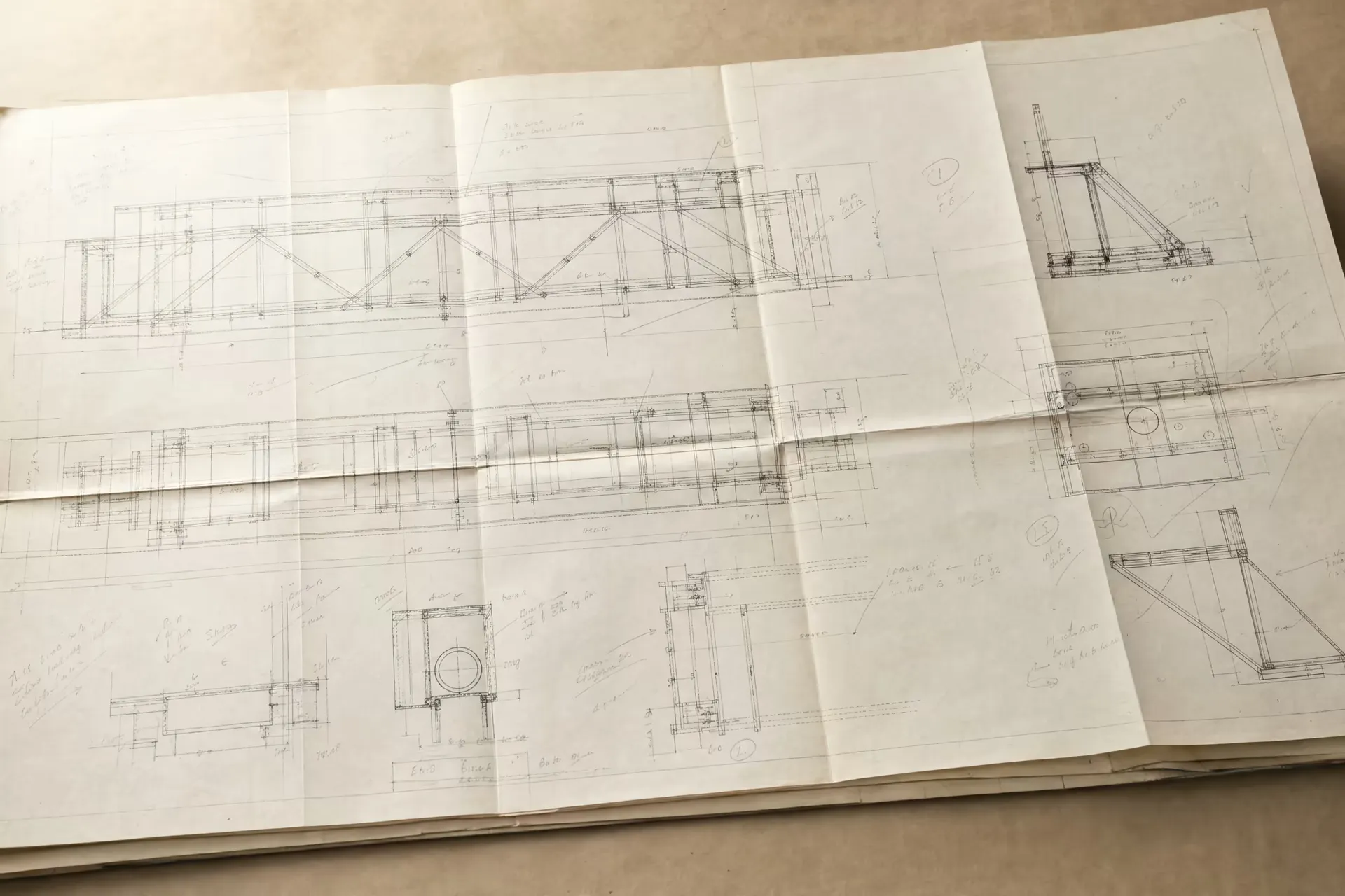 A folded engineering blueprint, fine drafting lines and dimension callouts crossing the creased paper in warm-tone monochrome.