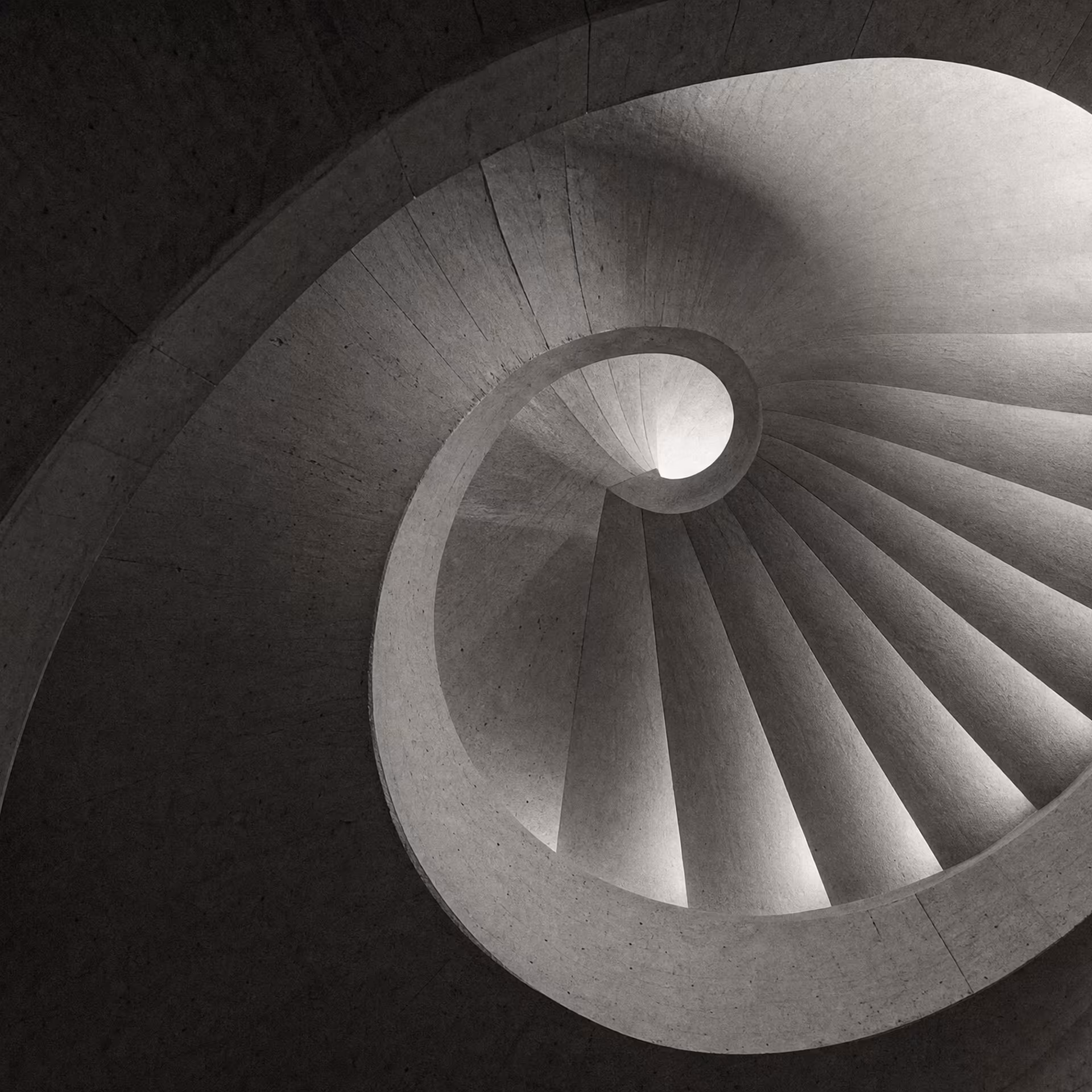 Cast-concrete spiral stair lit from a central oculus.